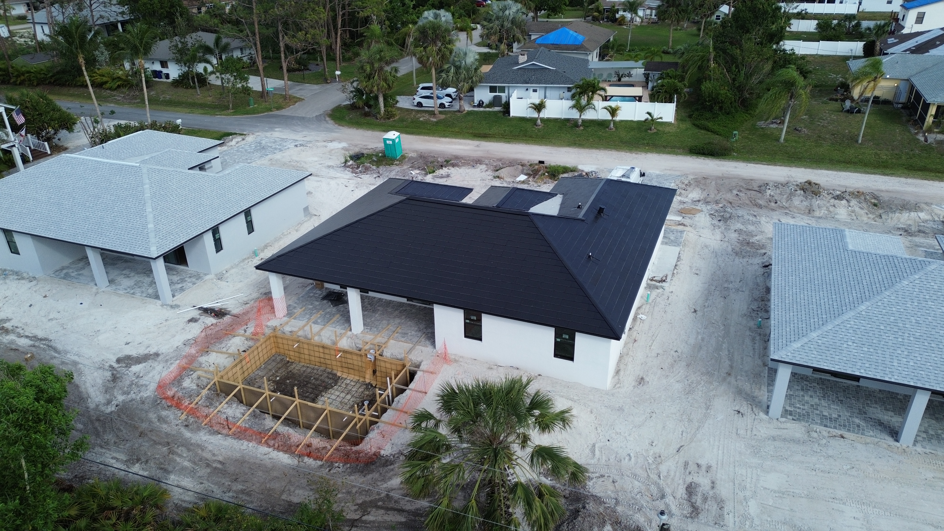 Aerial view of a PrimeBid custom home mid-construction with pool forming